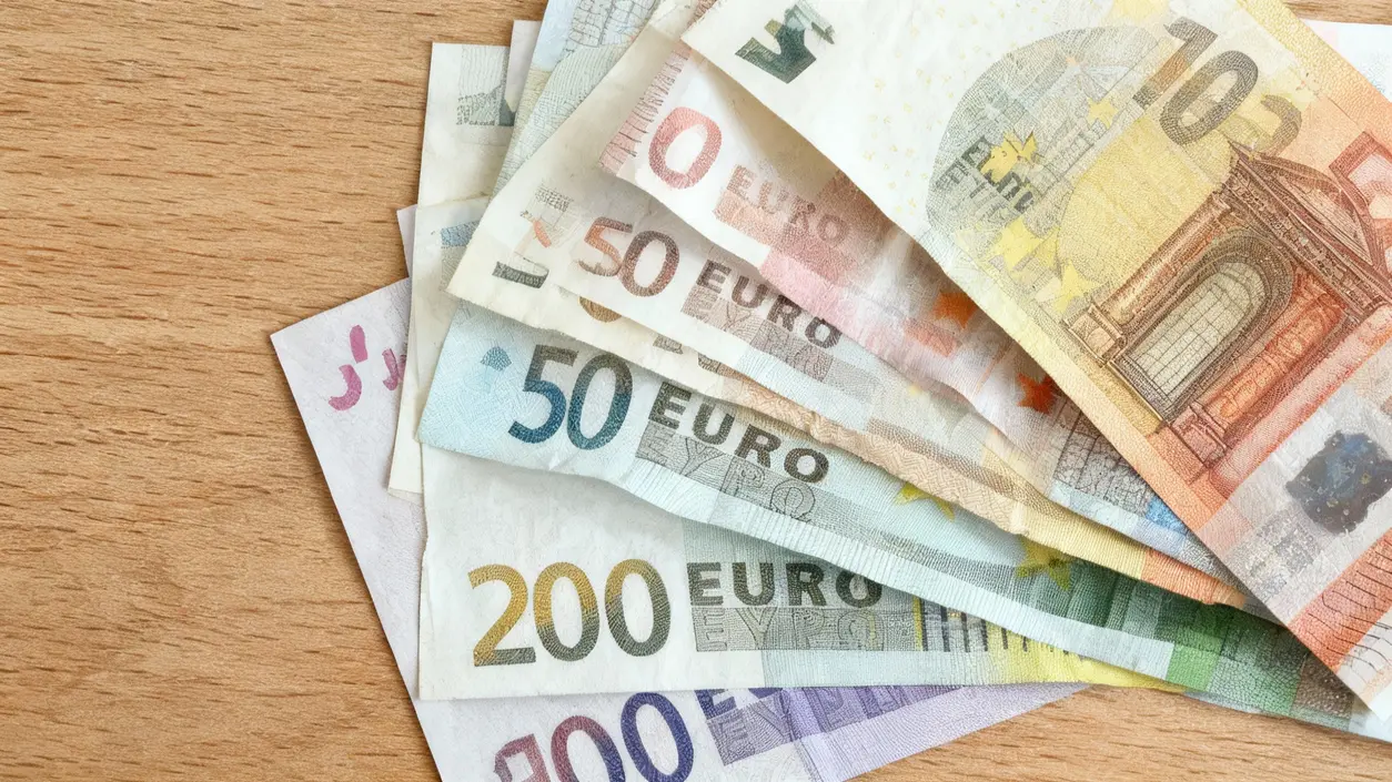 Banconote in euro disposte a ventaglio su una superficie in legno