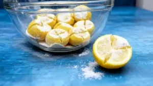 Limoni tagliati e cosparsi di sale in una ciotola di vetro su una superficie blu