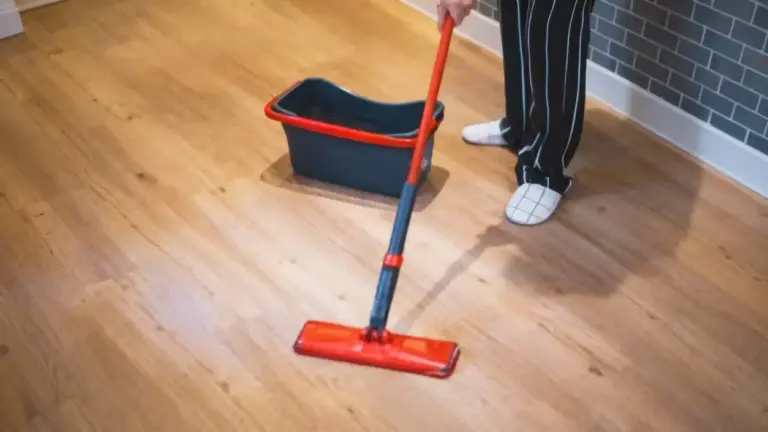 Persona che pulisce un pavimento in parquet con un mocio rosso e secchio