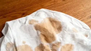 Macchia gialla di sudore ostinata su un tessuto bianco poggiato su una superficie in legno