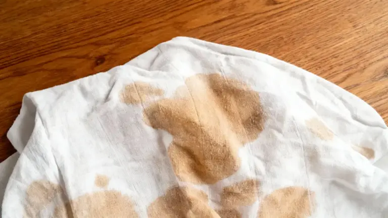 Macchia gialla di sudore ostinata su un tessuto bianco poggiato su una superficie in legno