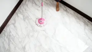 Una persona pulisce un pavimento in marmo con un mocio rosa