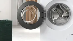 Oblò aperto di una lavatrice con alcuni panni all'interno e un cesto vicino.