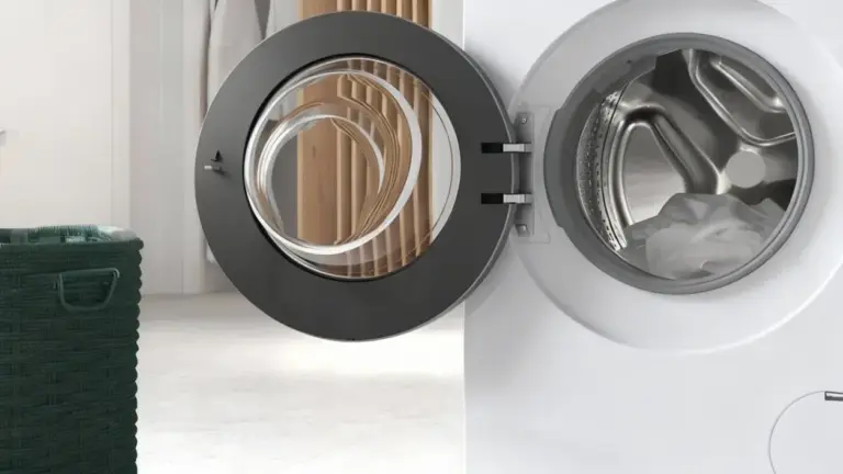 Oblò aperto di una lavatrice con alcuni panni all'interno e un cesto vicino.