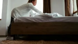 Una persona che sistema un letto in una stanza luminosa con tende marroni