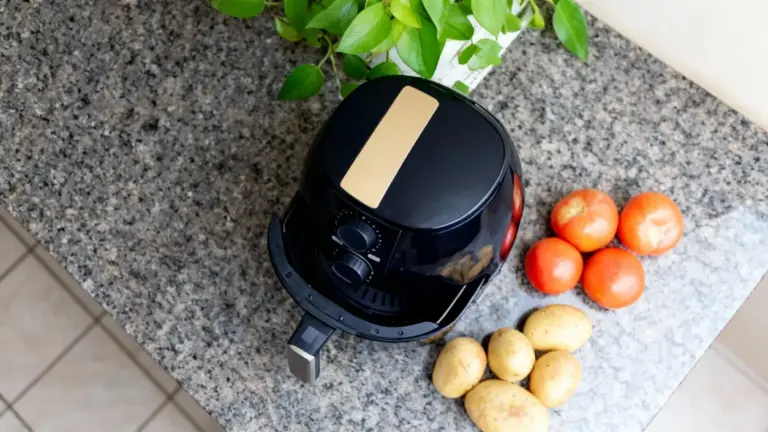 Friggitrice ad aria su piano cucina accanto a pomodori e patate