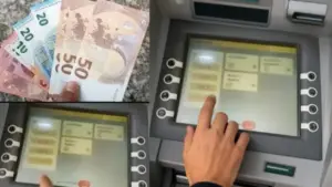 Una persona preleva denaro da uno sportello bancomat e tiene in mano banconote in euro